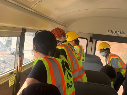 Employees on a bus with yellow vests