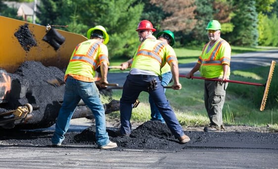 Construction workers paving road outside